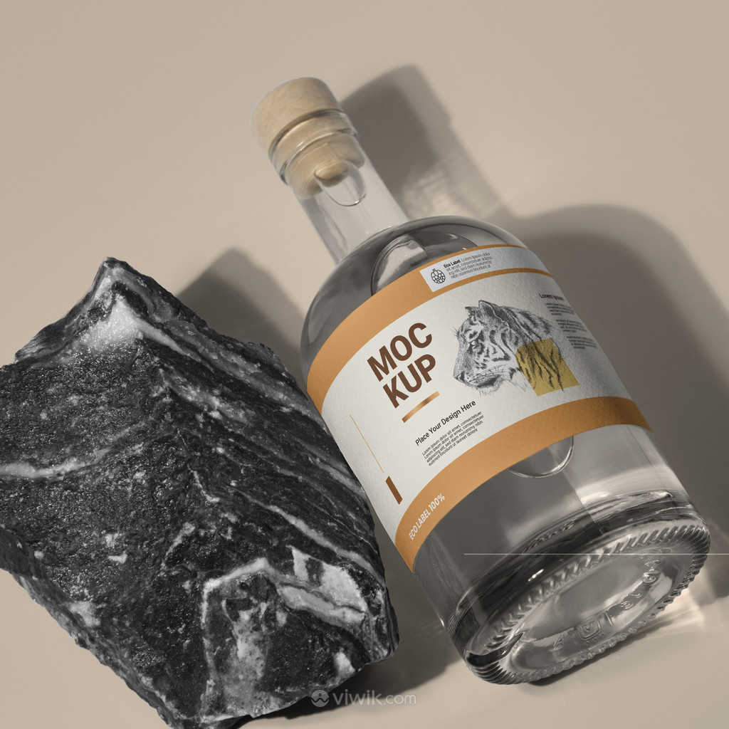石头旁边带木塞的透明玻璃瓶酒瓶包装贴图样机