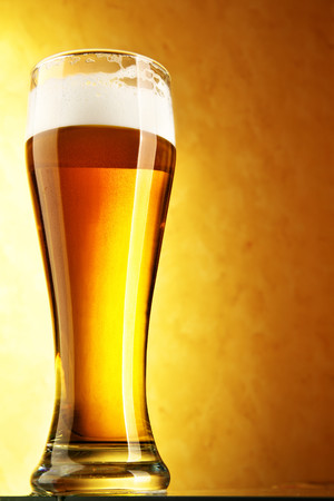 黄色背景装满啤酒饮料的玻璃杯图片