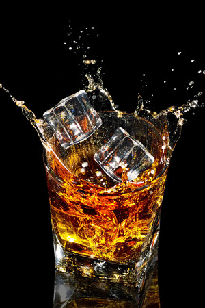冰块加入威士忌酒杯酒水飞溅的图片