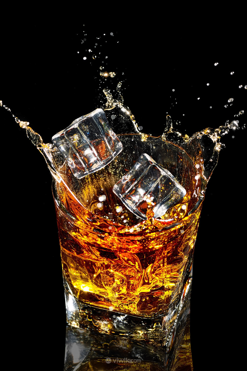 冰块加入威士忌酒杯酒水飞溅的图片